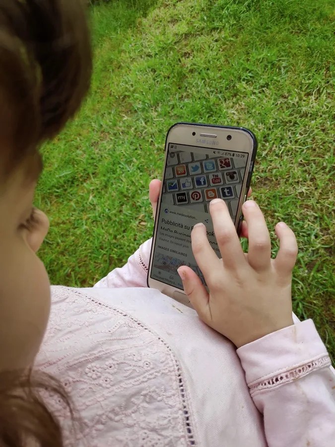 Una menor consulta un teléfono móvil.